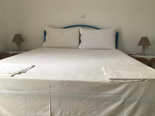 a large white bed with white sheets and pillows at Villa Maria in Kamariotissa