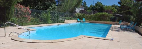 a large swimming pool with blue water in a yard at Logis Hotel Le Prince Noir in Sérignac-sur-Garonne