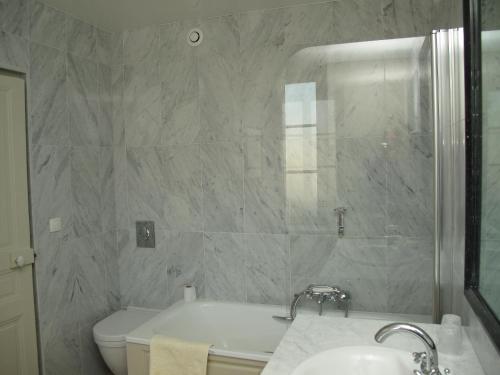 y baño con bañera, aseo y lavamanos. en Hôtel de Londres en Fontainebleau