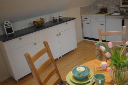 a kitchen with white cabinets and a table with chairs at Ferienwohnung Gulde N tal in Waldhilbersheim