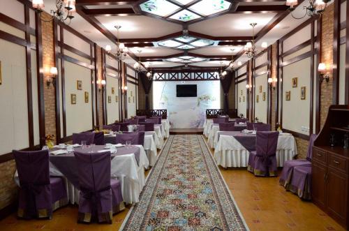 una habitación llena de mesas con sillas moradas y una pantalla en Hotel Miss Mari, en Karagandá