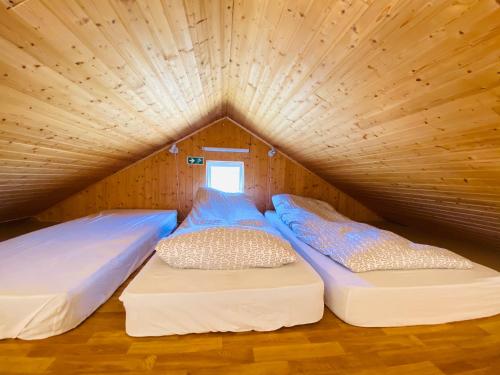 two beds in a room with a wooden ceiling at Ábót - Riverside Cottage in Egilsstadir