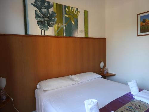 フィウミチーノにあるB&B Isolaの白いベッド1台(木製ヘッドボード付)が備わるベッドルーム1室が備わります。