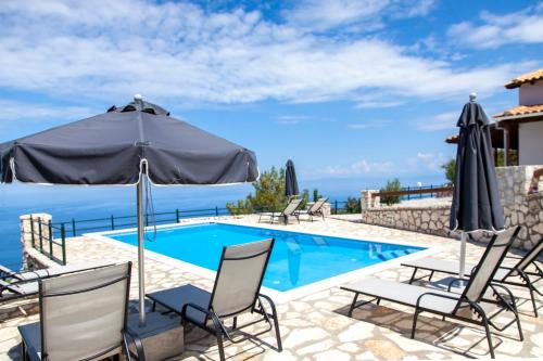 a villa with a swimming pool with chairs and an umbrella at Villa Skyfall in Kalamitsi