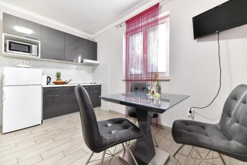uma cozinha com uma mesa e duas cadeiras pretas em Pool house LUKA em Zadar