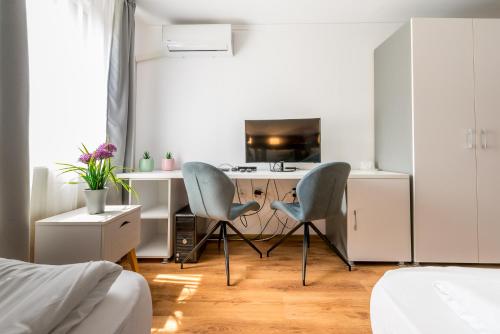 a bedroom with a desk with two chairs and a kitchen at Pensiunea Armonia in Nădăşelu