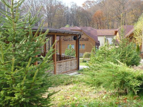 a log cabin with a deck in a yard with trees at Erney Laz Hotel in Shaian