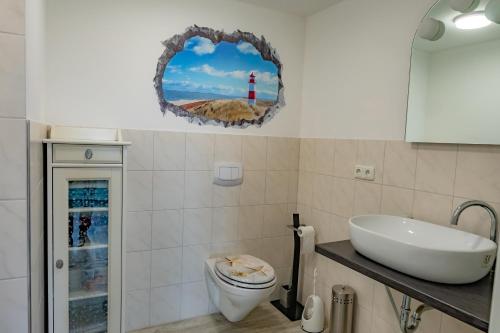 ein Badezimmer mit einem Waschbecken, einem WC und einem Leuchtturm in der Unterkunft Fehmarn Relax in Burg auf Fehmarn