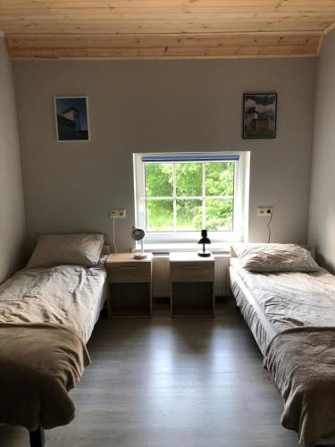 two beds in a room with a window at Metsalagendik in Otepää