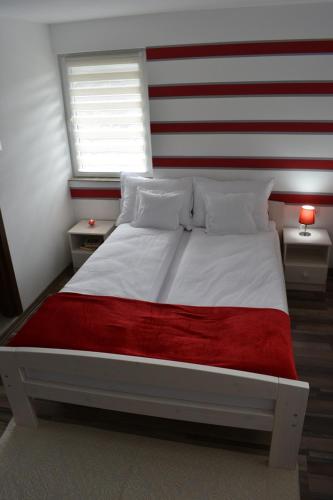 Una cama grande con cabecera de rayas rojas y blancas. en Casa DODÓ Vendégház, en Praid