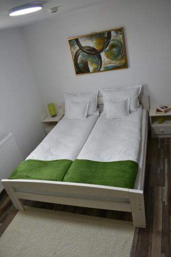 Bett mit grüner Decke auf einem Zimmer in der Unterkunft Casa DODÓ Vendégház in Praid