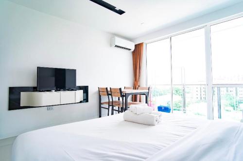a bedroom with a white bed with a tv on the wall at City Center Residence in Pattaya Central
