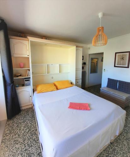 une chambre avec un grand lit blanc avec des oreillers orange dans l'établissement Appartement plein sud les Cyclades, au Lavandou