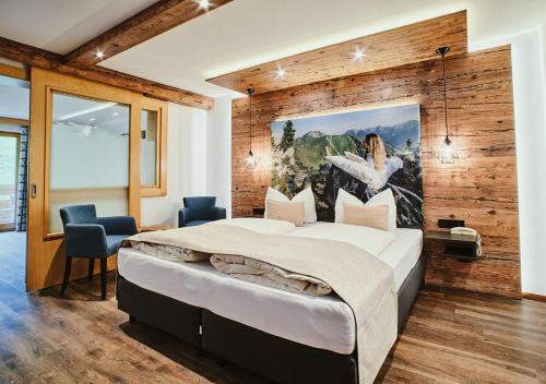 a bedroom with a large bed with a painting on the wall at Hotel Rustika in Lermoos