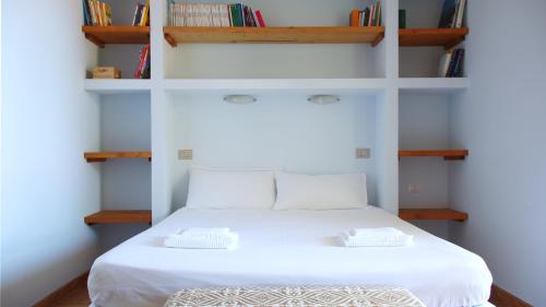 Schlafzimmer mit einem weißen Bett und Bücherregalen in der Unterkunft Welcomely - Sardinian Stone House in Torre Grande