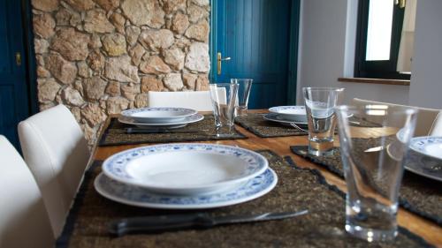 a table with plates and glasses on top of it at Sardinianworld - Sardinian Stone House in Torre Grande