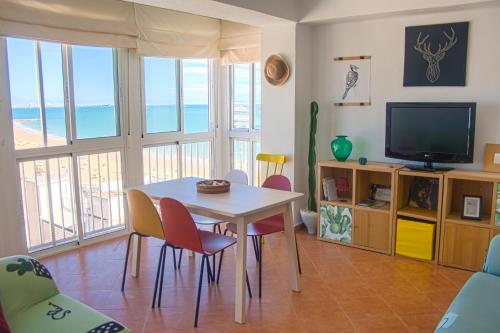 a living room with a table and chairs and a television at Una ventana al mar in Rota