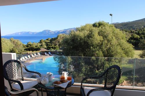 a table with food on top of a balcony with a pool at I Ginepri Hotel in Cala Gonone