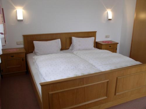 a large bed in a room with two night stands at Haus Waldfriede in Pertisau