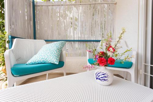 a vase with flowers on a table with two chairs at B&B Auliv in Mattinata