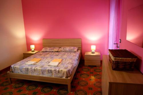 1 dormitorio con 1 cama con paredes de color rosa y 2 lámparas en Casa Vacanze Vecchia Torre, en Gallipoli