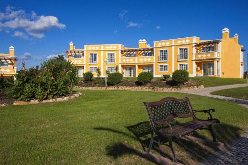 a bench in front of a large yellow building at Colina da Lapa & Villas in Carvoeiro