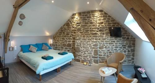 une chambre avec un lit et un mur en pierre dans l'établissement Le Cottage de L Abbaye, à Lonlay-lʼAbbaye
