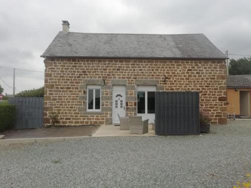 un piccolo edificio in mattoni con una porta bianca di Le Cottage de L Abbaye a Lonlay-lʼAbbaye