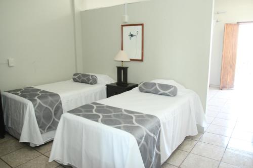 two beds in a room with white walls at Hotel Posada Doña Rubino in Mazatlán