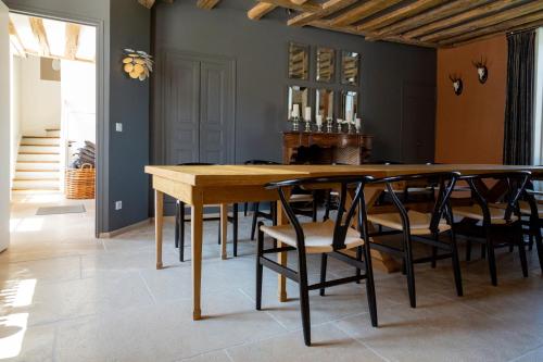 uma sala de jantar com uma mesa de madeira e cadeiras em Ferme du Château em Anthenay