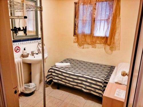 a small bathroom with a bed and a sink at AB Pension Granada in Granada