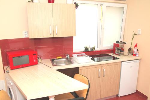 オラデアにあるyox apartment 5の小さなキッチン(赤い電子レンジ付きのカウンター付)