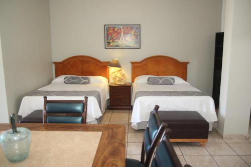 a hotel room with two beds and a table at Hotel Posada Doña Rubino in Mazatlán