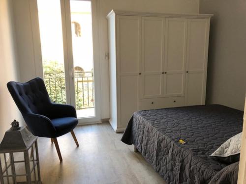 um quarto com uma cama, uma cadeira e uma janela em F2 + GARAGE RESIDENCE FRONT DE MER em Banyuls-sur-Mer