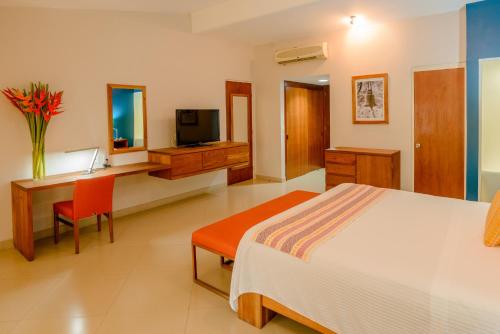 een slaapkamer met een bed, een bureau en een televisie bij Hotel Loma Real in Tapachula