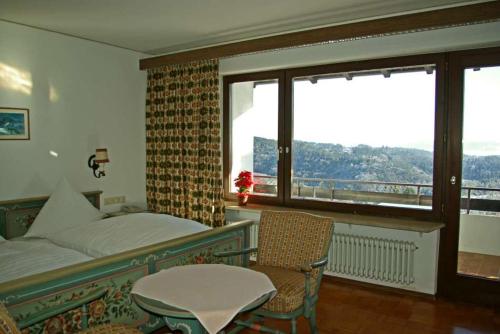 Schlafzimmer mit einem Bett, einem Tisch und einem Fenster in der Unterkunft Panoramahotel Alde Hotz GbR in Görwihl