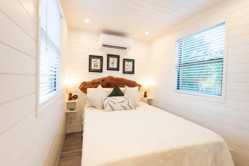 a bedroom with a bed with white sheets and a window at The Woods- Container Tiny House 12 min to Magnolia/Baylor/Downtown in Bellmead