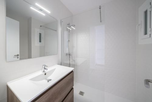 La salle de bains blanche est pourvue d'un lavabo et d'une douche. dans l'établissement Apartment Sofia, à L'Escala