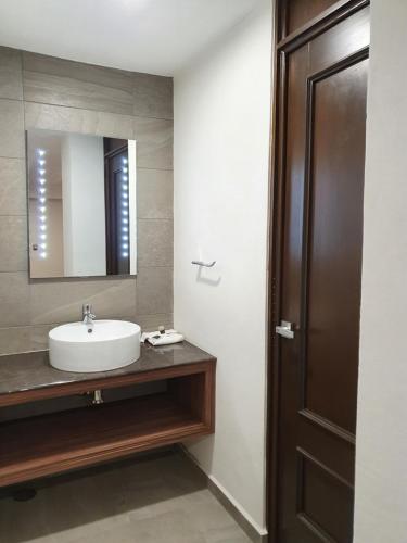 W łazience znajduje się umywalka i lustro. w obiekcie Estanza Hotel & Suites w mieście Morelia