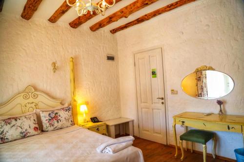 a bedroom with a bed and a desk and a mirror at Sari Gelin Alacati Hotel in Alacati