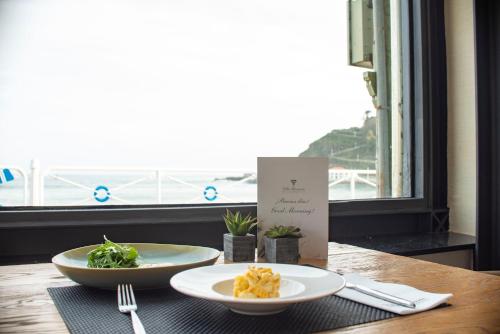 a table with two plates of food and a window at Hotel Villa Rosario, Palacete in Ribadesella