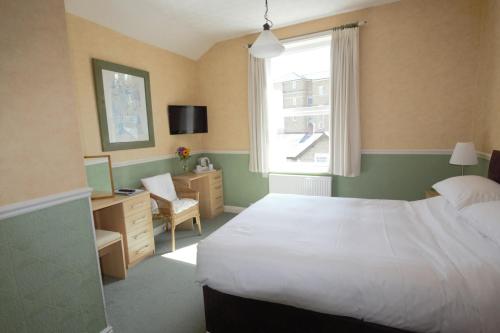 a bedroom with a bed and a desk and a window at The Dales in Harrogate