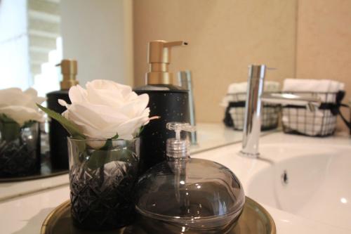 a bathroom sink with a bottle of soap and a flower at Slope Design Villa - Architecture villa with private pool in Ponte de Lima