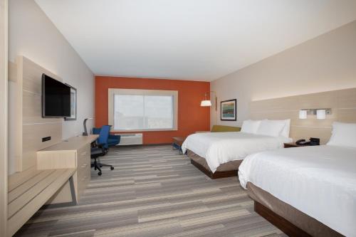 a hotel room with two beds and a flat screen tv at Holiday Inn Express & Suites - Denver NE - Brighton by IHG in Brighton