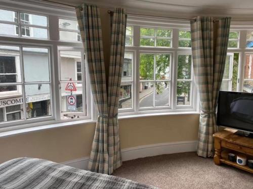 a bedroom with windows and a bed and a television at King William IV in Totnes