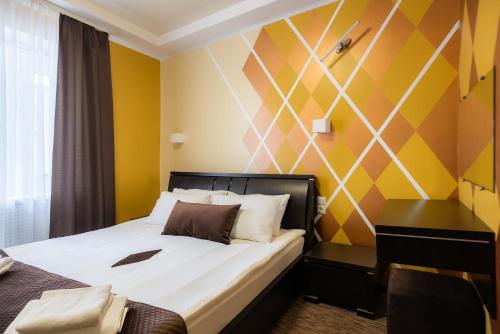a bedroom with a bed and a yellow wall at Rhombus Hotel in Luts'k