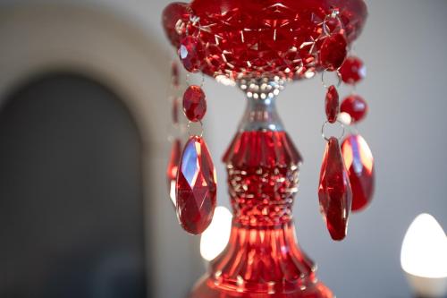 a red glass vase with beads and earrings on it at Átrium Rooms & Café in Sopron