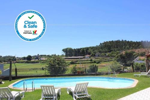 a swimming pool with chairs and a sign that says clean and safe at Vivenda Mendes in Outeiro