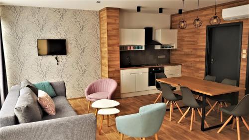 een woonkamer met een bank en een tafel en stoelen bij Erdőalja 11 Apartman in Nyíregyháza