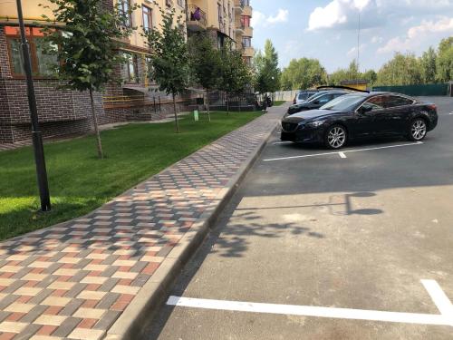 a car parked in a parking lot next to a sidewalk at Luxury Emerald Apartments in Irpin'